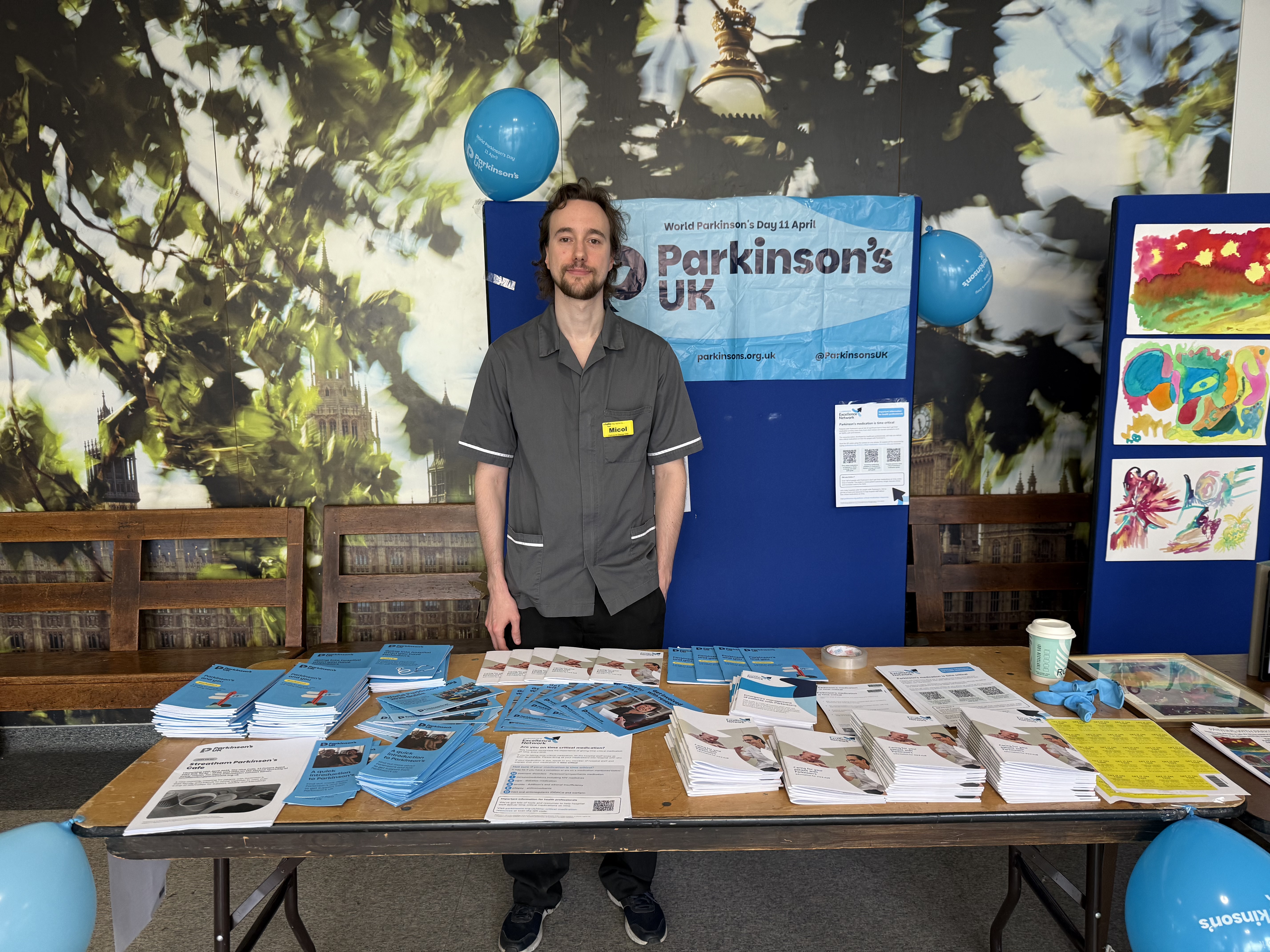 A nurse stands behind a table with lots of different Parkinson's UK leaflets.