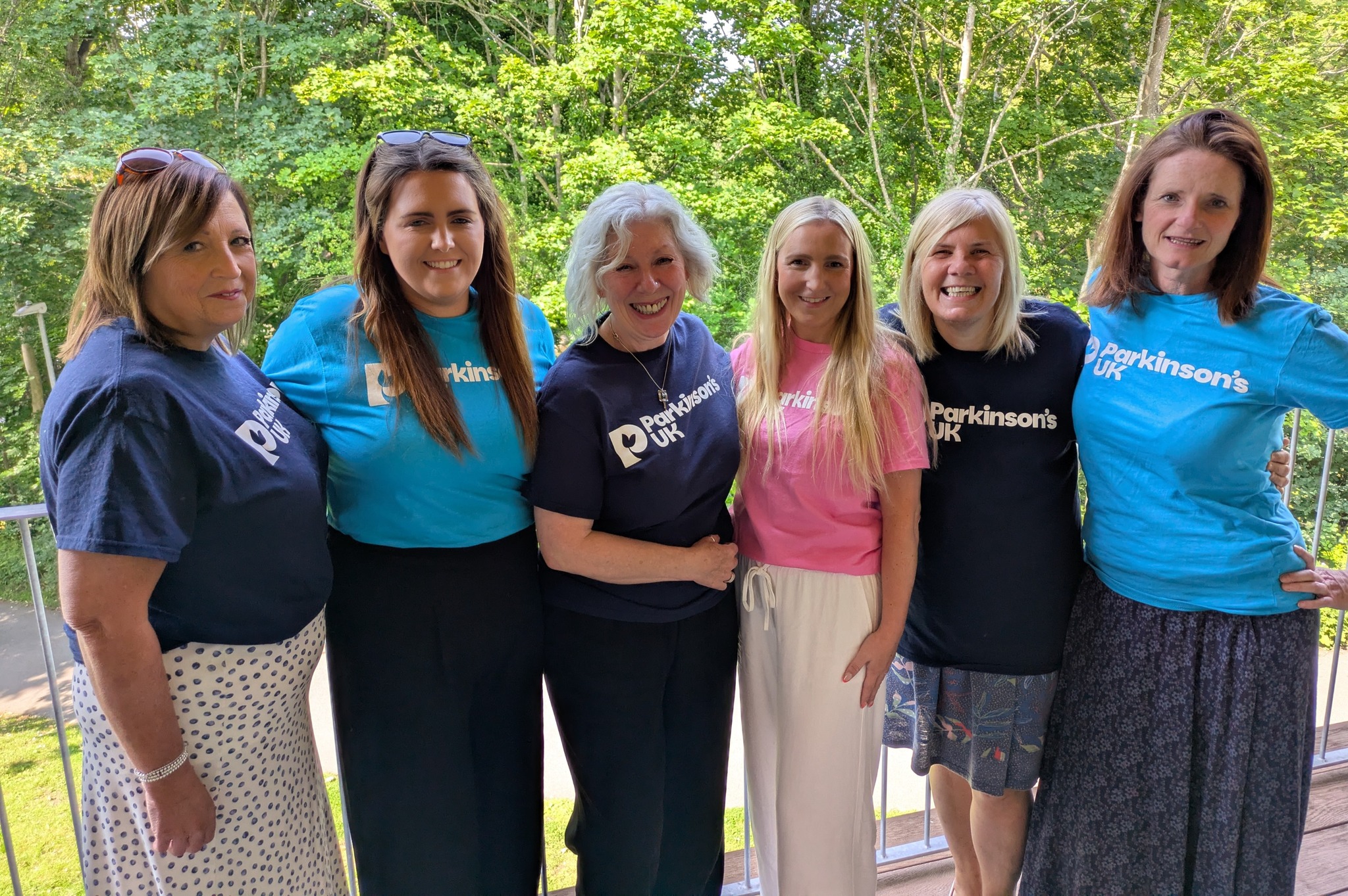 Our Local Advisors in Wales standing in a line, all female and wearing Parkinson's UK branded t-shirts in various colours. 