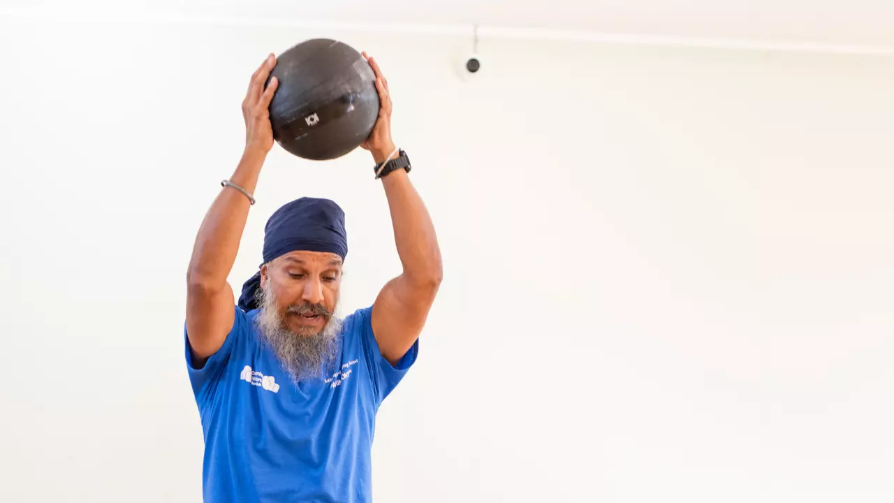 An image of a Parkinson's boxing instructor taking a strength demonstration. He is wearing a blue top and dark blue trousers.
