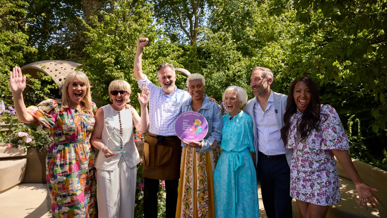 A group of people stood in the Parkinson's UK RHS Chelsea Flower Show Garden holding an award and cheering