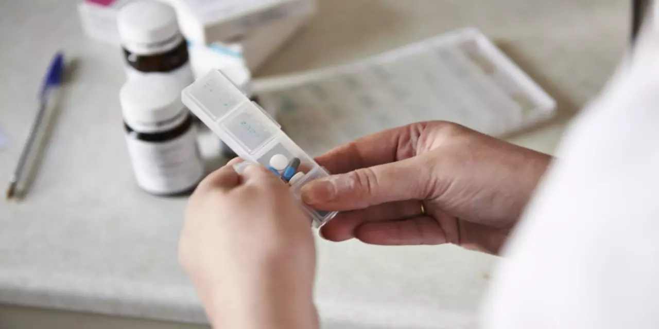 A lady is taking Parkinson's medication our of a pill box
