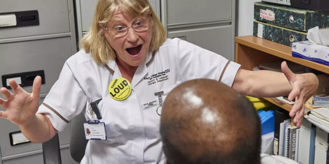 Speech and language therapist takes a person with Parkinson's through some exercises.