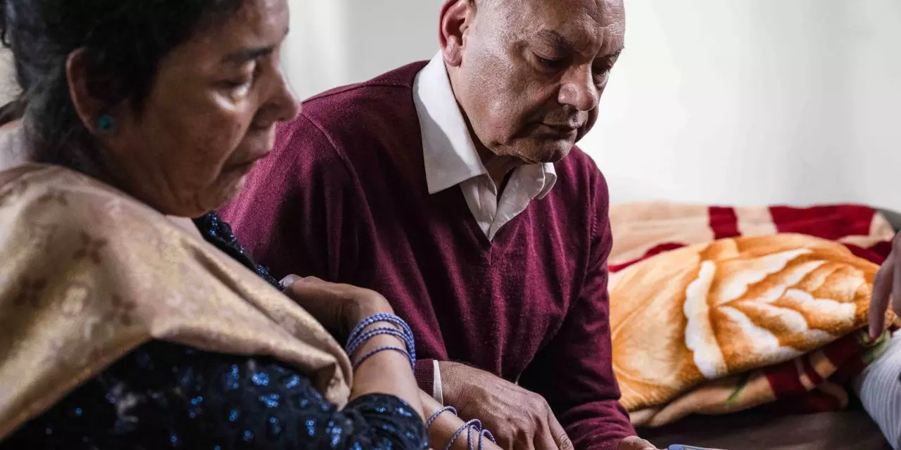 A man helping his wife by taking her blood sugar