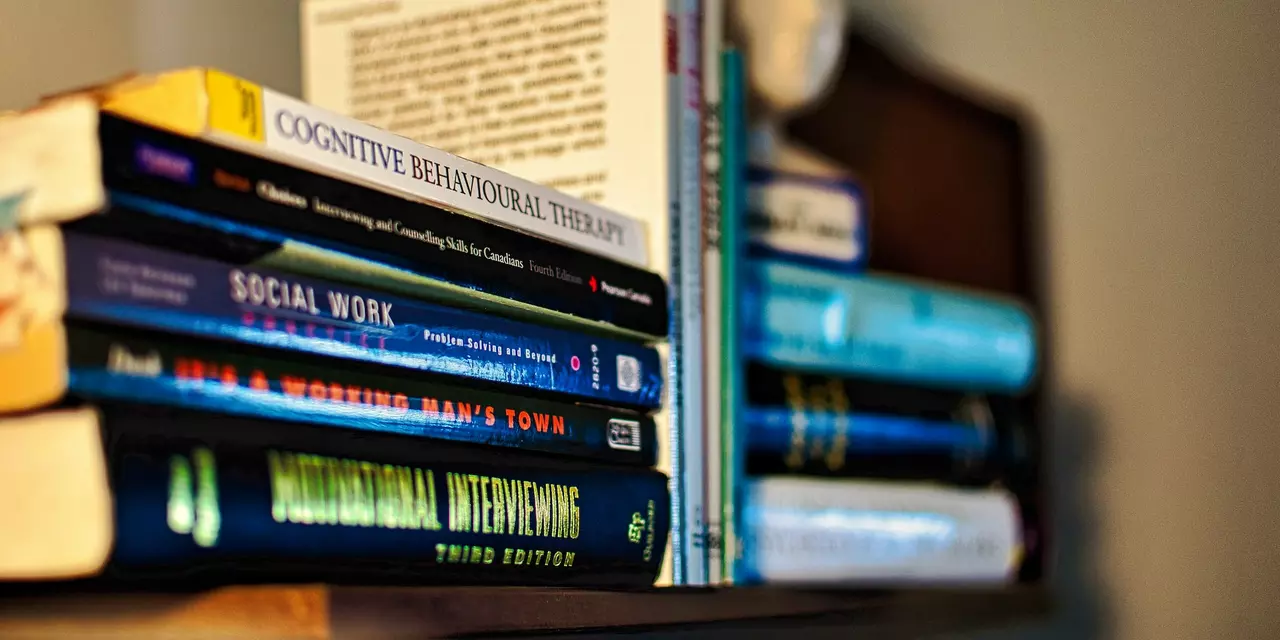 Two piles of books, laying on their side. The title of the book in focus is 'Cognitive Behavioural Therapy'