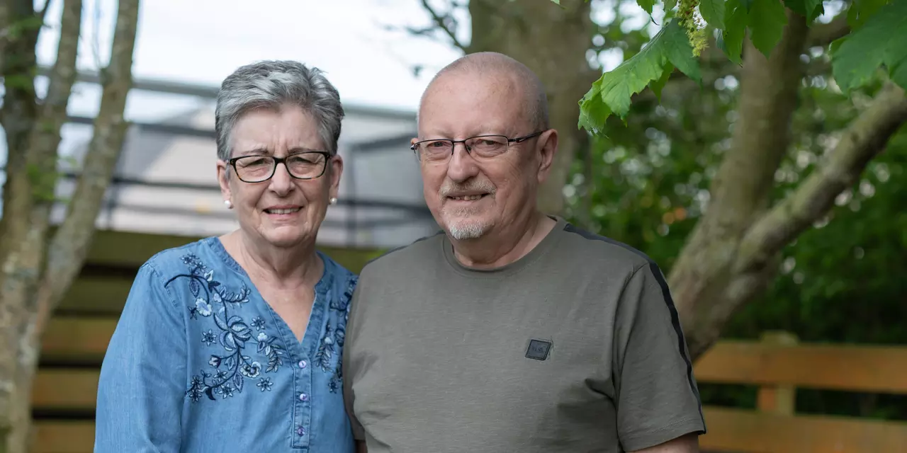 John and Susan smiling to camera in their garden