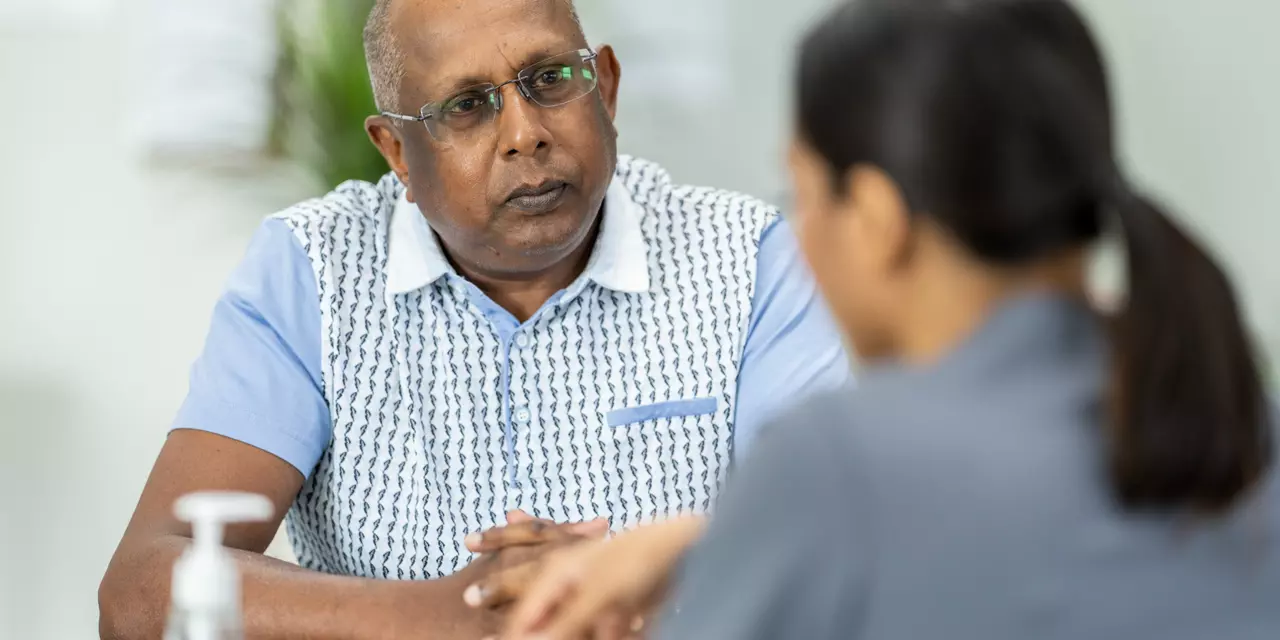 A man with glasses facing the camera and talking to a woman 