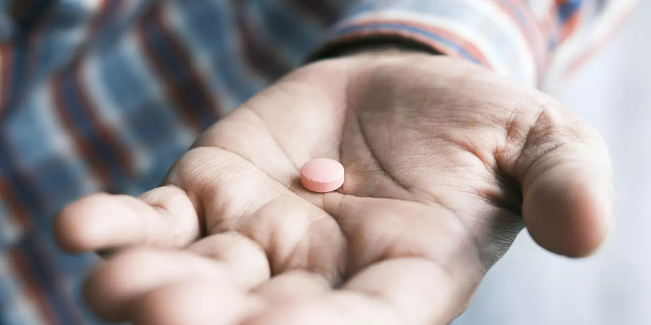 Hand holding a small pill