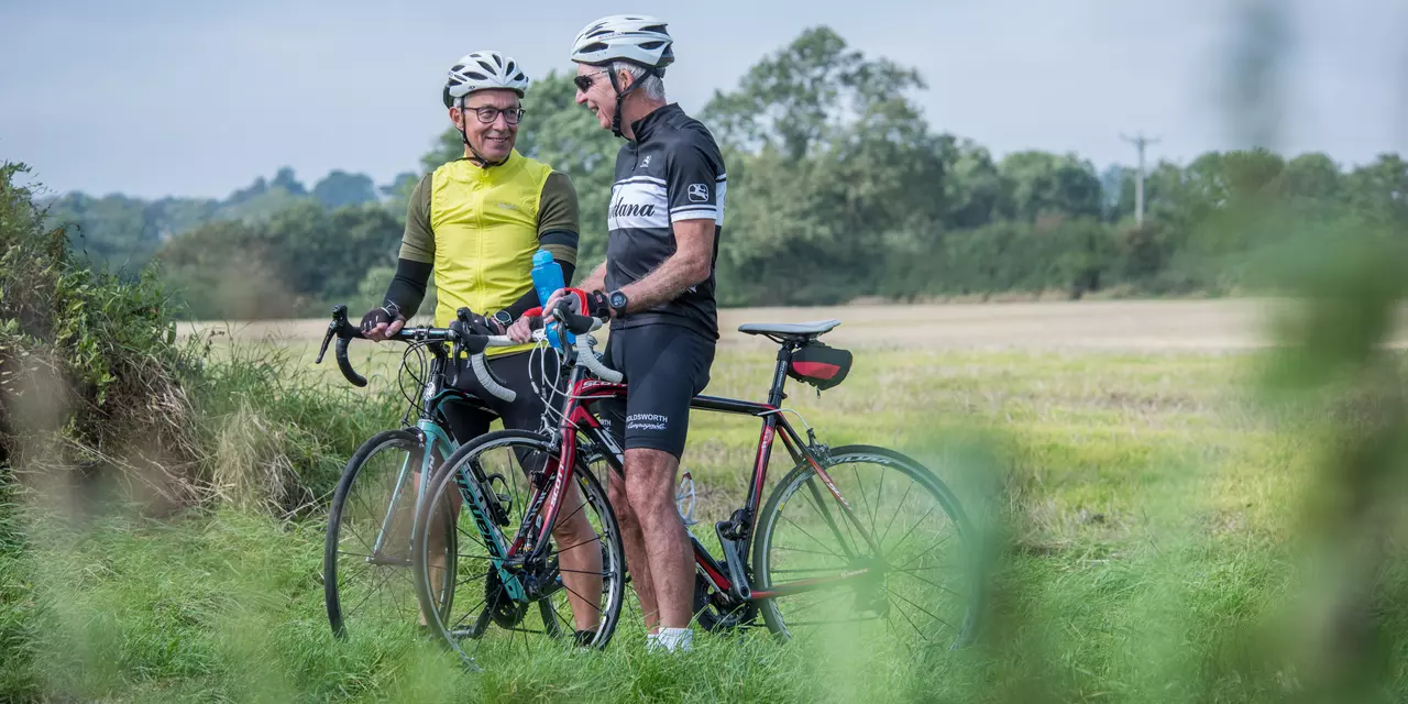 two men on their bikes in cycle gear, talking to each other 