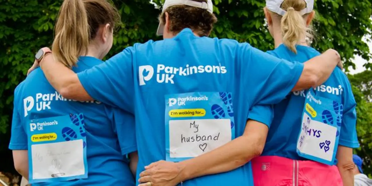 Three women with their arms around each other showing their walk for Parkinsons stickers 