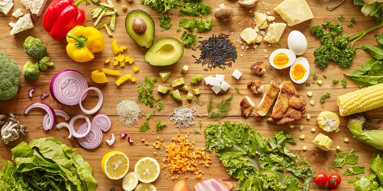 A selection of fruits, vegetables, breads, nuts and protein sources displayed on a wooden board