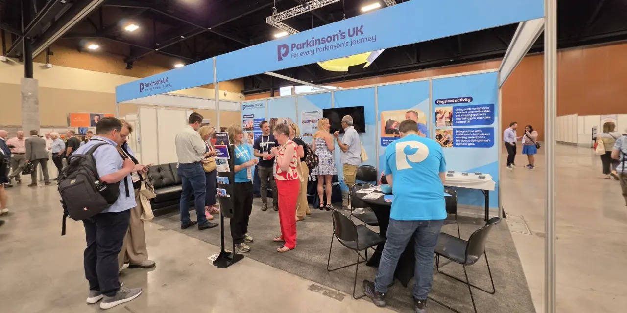 The Parkinson's UK stand at the World Parkinson Congress in Arizona, showing many people engaging in chats and activities at the stand