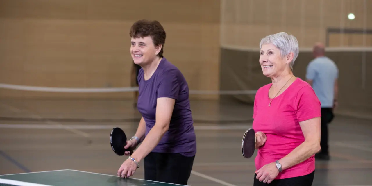 An image of two women playing table tennis at a leisure centre.