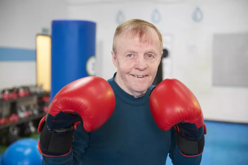 Tommy wearing boxing gloves, smiling at the camera