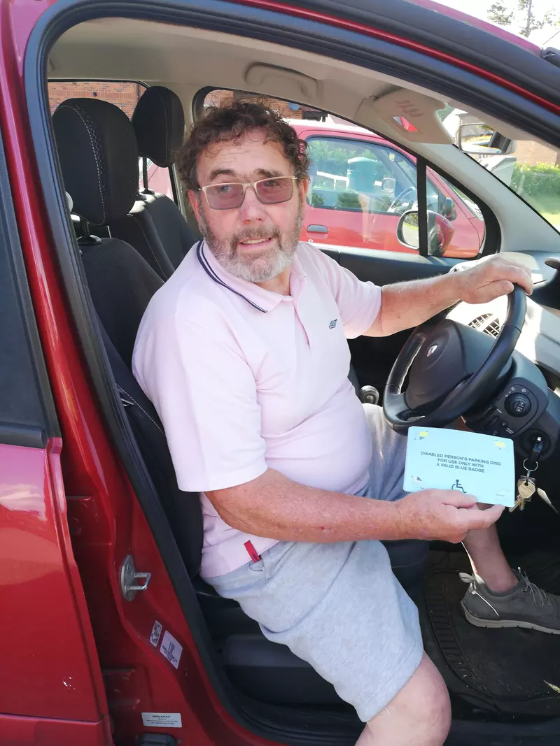 Alan sat in the driving seat, holding his Blue Badge