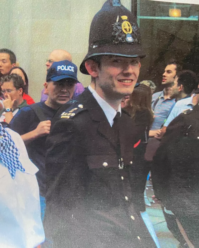A man marching in a pride parade wearing a policeman's uniform