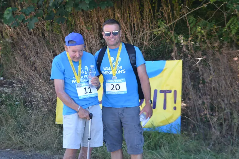 John and his son Gary at the finish line of Walk for Parkinson's event. Both are wearing Parkinson's tshirts and shorts.