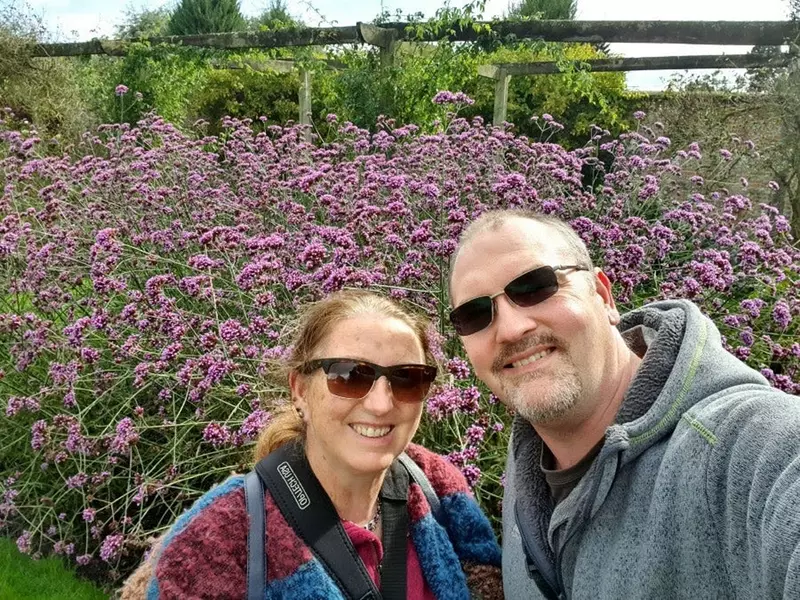Fiona and her husband Andy with flowers behind them