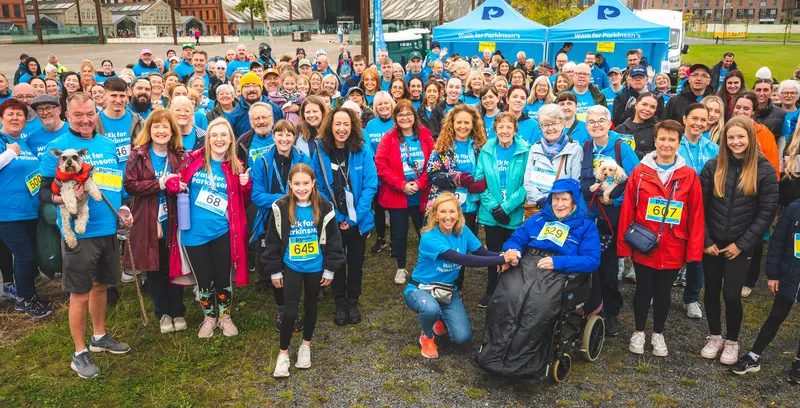A large group of fundraisers in their Parkinson's UK t-shirts, smiling for a group photo outside. 