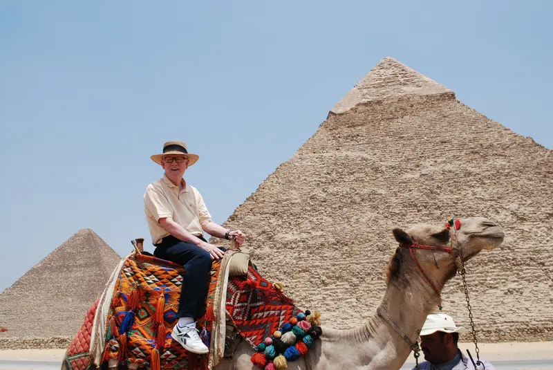 PhD research Linda Bryant's father riding a camel in Egypt opposite the pyramids
